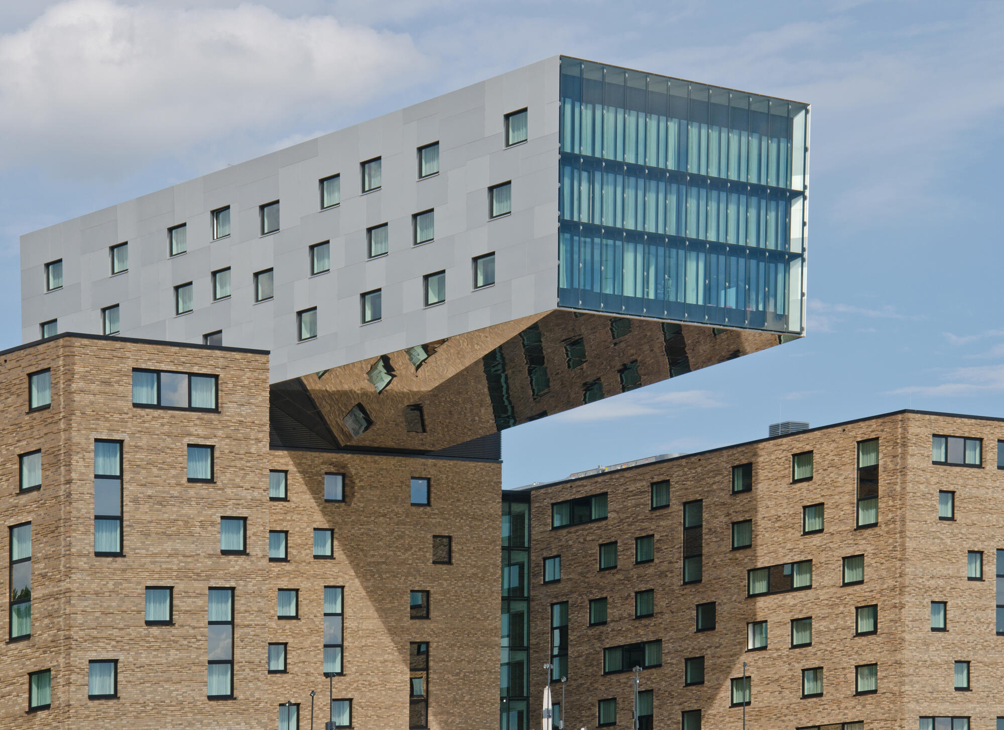 Der weit auskragende Gebäudeteil des nhow-Hotels über einer Backsteinfassade am Berliner Spreeufer.