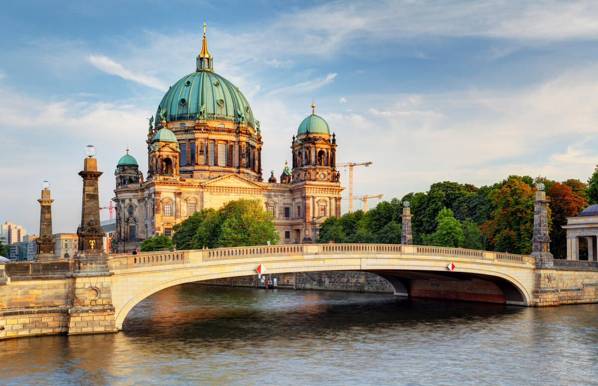 Die Friedrichsbrücke vor dem Berliner Dom, dessen Fassade von tief stehender Sonne beleuchtet wird.