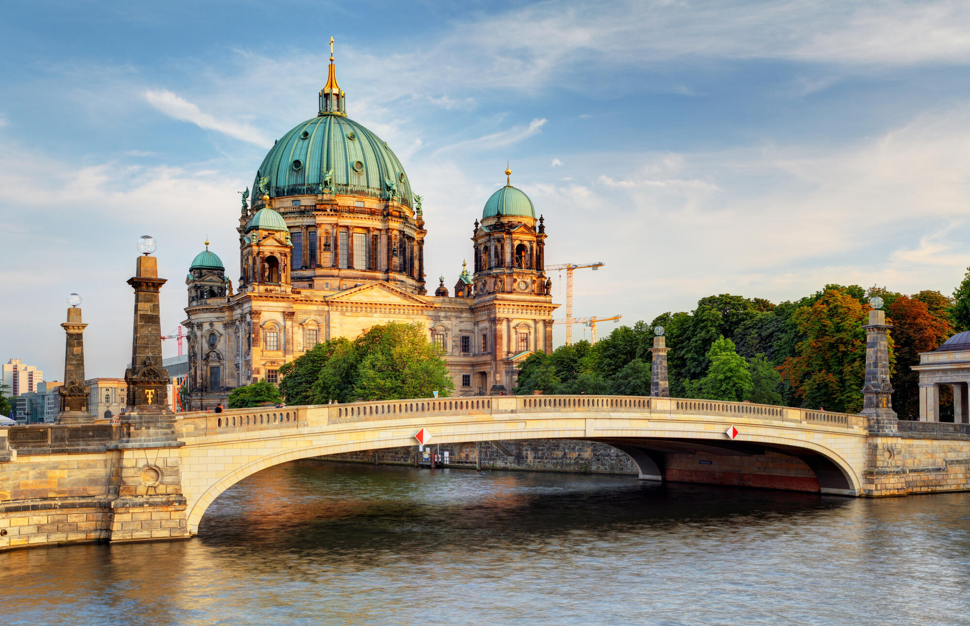 Die Friedrichsbrücke vor dem Berliner Dom, dessen Fassade von tief stehender Sonne beleuchtet wird.
