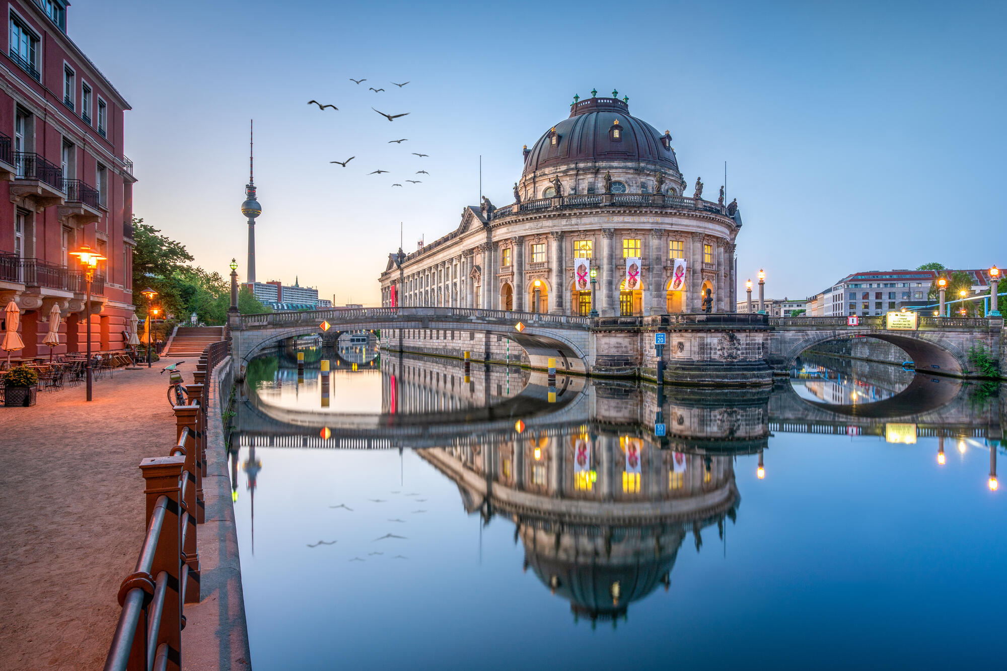 Das beleuchtete Bode-Museum und die Monbijoubrücke spiegeln sich in der Spree; links steht der Fernsehturm.