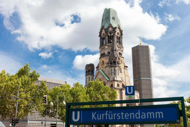 Die Kaiser-Wilhelm-Gedächtniskirche mit altem und neuem Turm hinter dem U-Bahn-Eingang Kurfürstendamm.