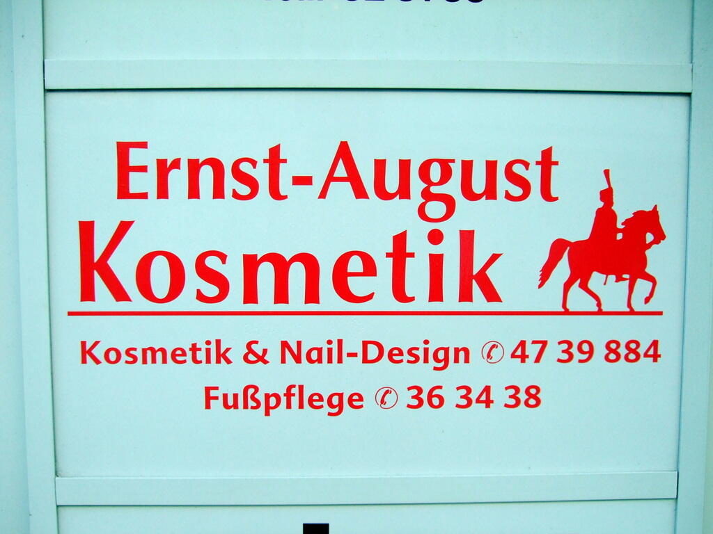 Hellblaues Türschild mit roter Aufschrift für Ernst-August Kosmetik sowie Kosmetik, Nail-Design und Fußpflege.