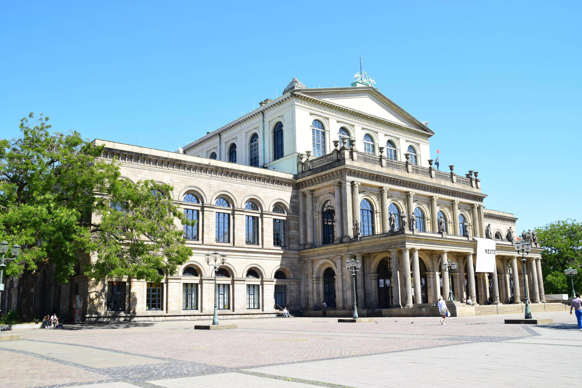Das Opernhaus Hannover mit einem grünen Baum bei blauem Himmel