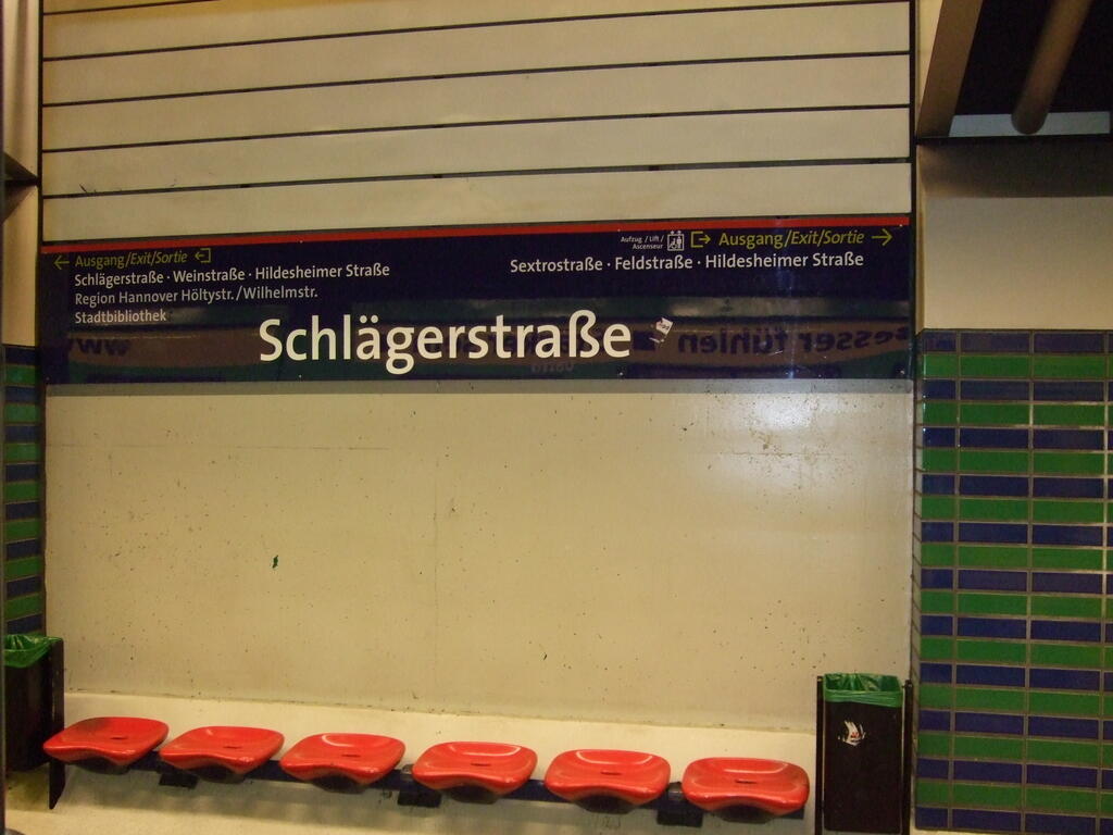 Rote Sitzschalen vor einer hellen Wand in der U-Bahn-Station Schlägerstraße.