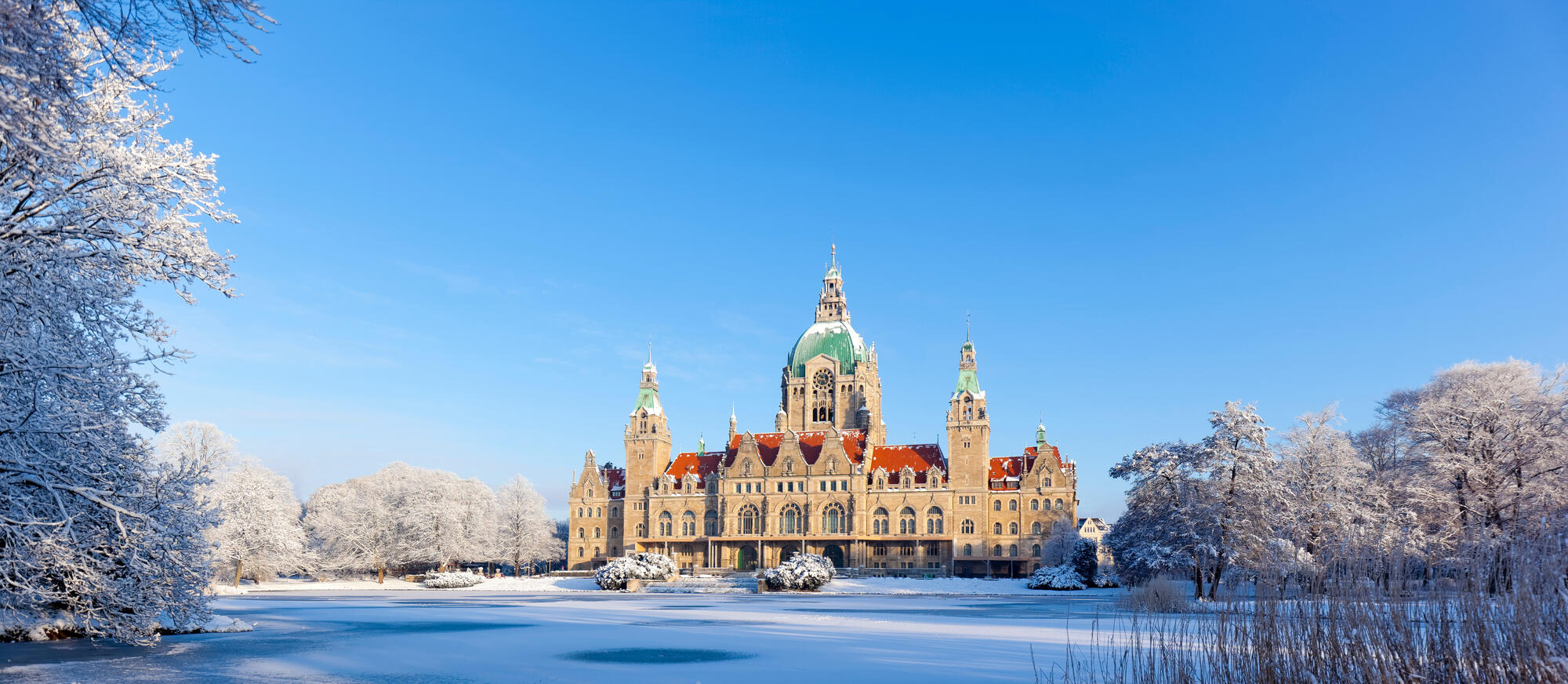 Das Neue Rathaus hinter dem zugefrorenen Maschteich an einem klaren Wintertag