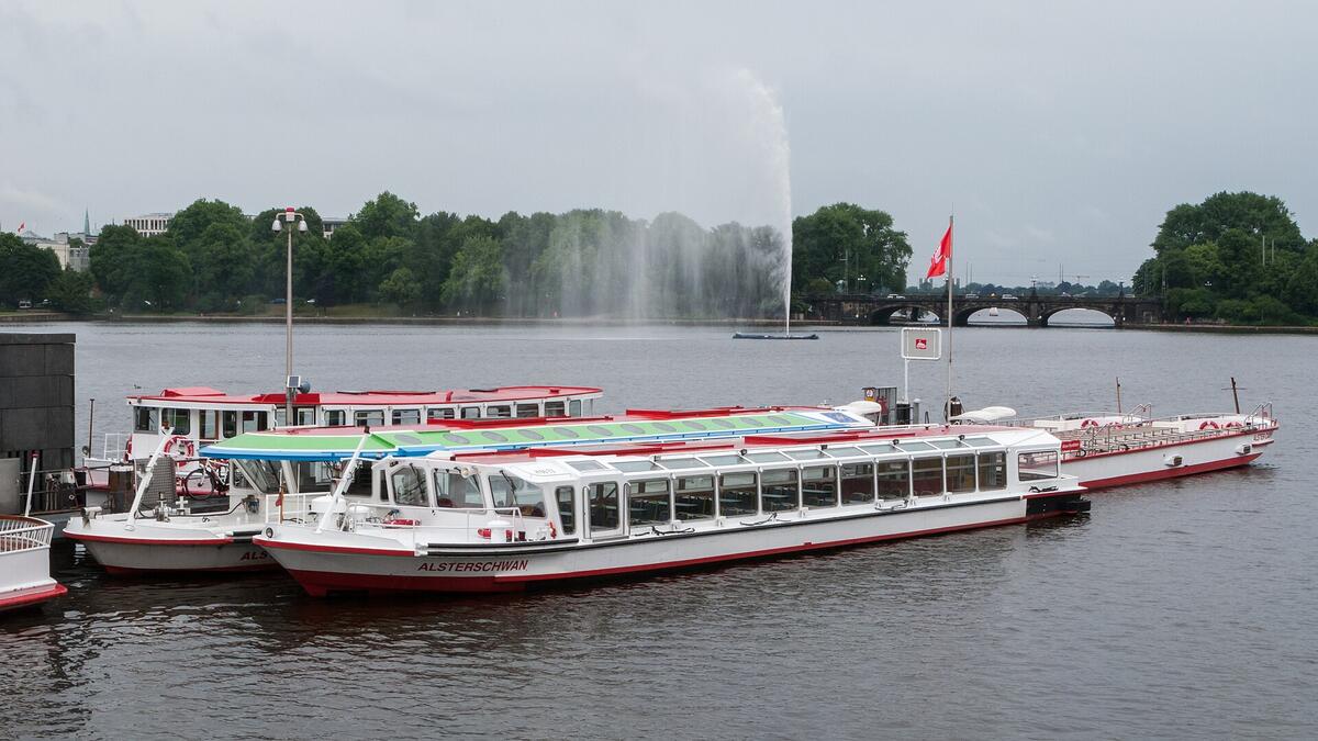 Anleger und Schiffe auf Hamburgs Binnenalster unter einem bewölkten Himmel.