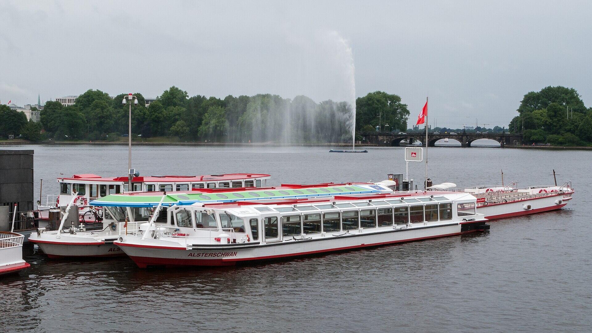 Anleger und Schiffe auf Hamburgs Binnenalster unter einem bewölkten Himmel.