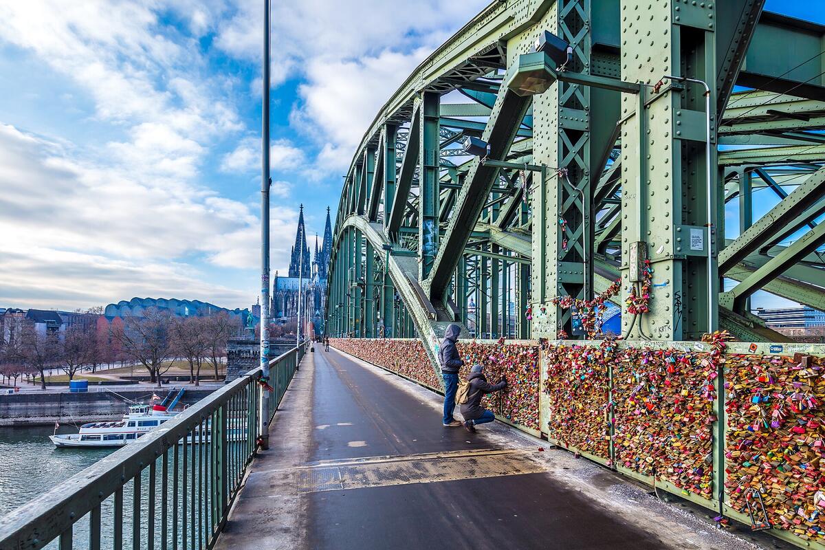 Fußweg mit Liebesschlössern auf der Hohenzollernbrücke; dahinter der Kölner Dom.