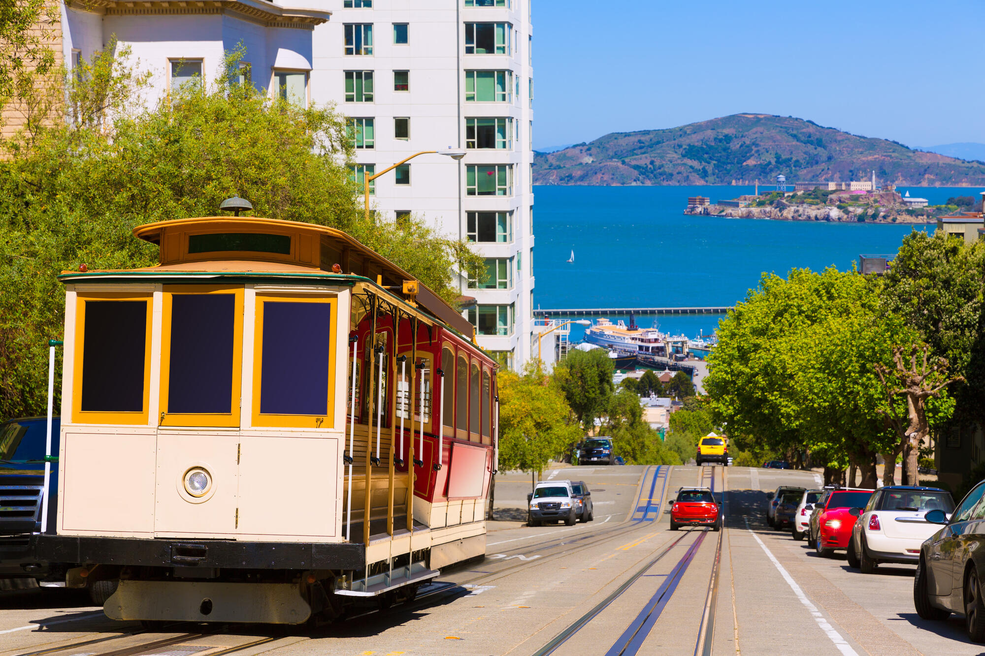 Ein Cable Car steht auf der steilen Hyde Street; zwischen den Häusern öffnet sich der Blick auf die Bucht.