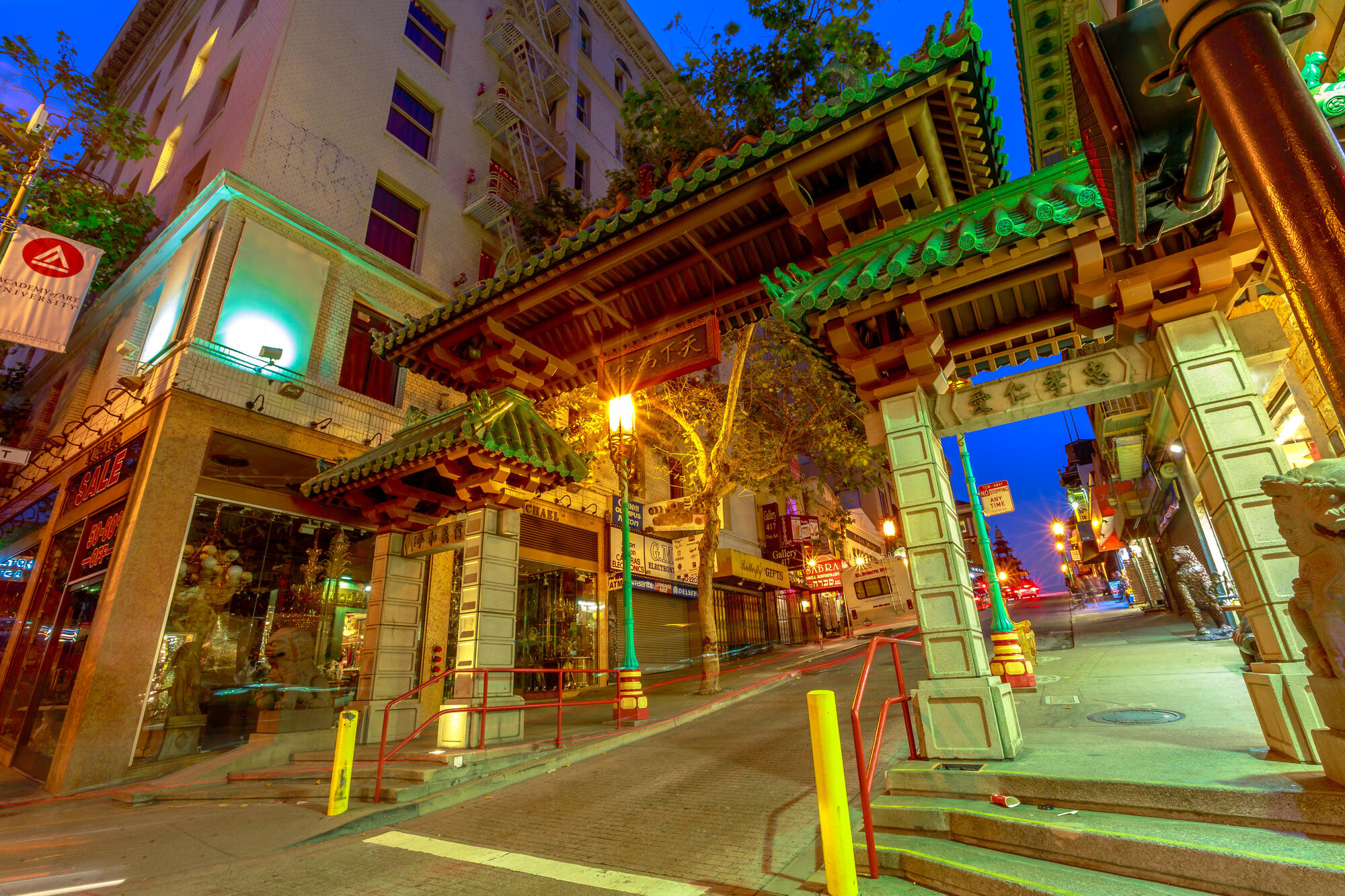 Das beleuchtete Chinatown-Tor mit grünen Dächern und verzierten Stützen überspannt den Straßeneingang.