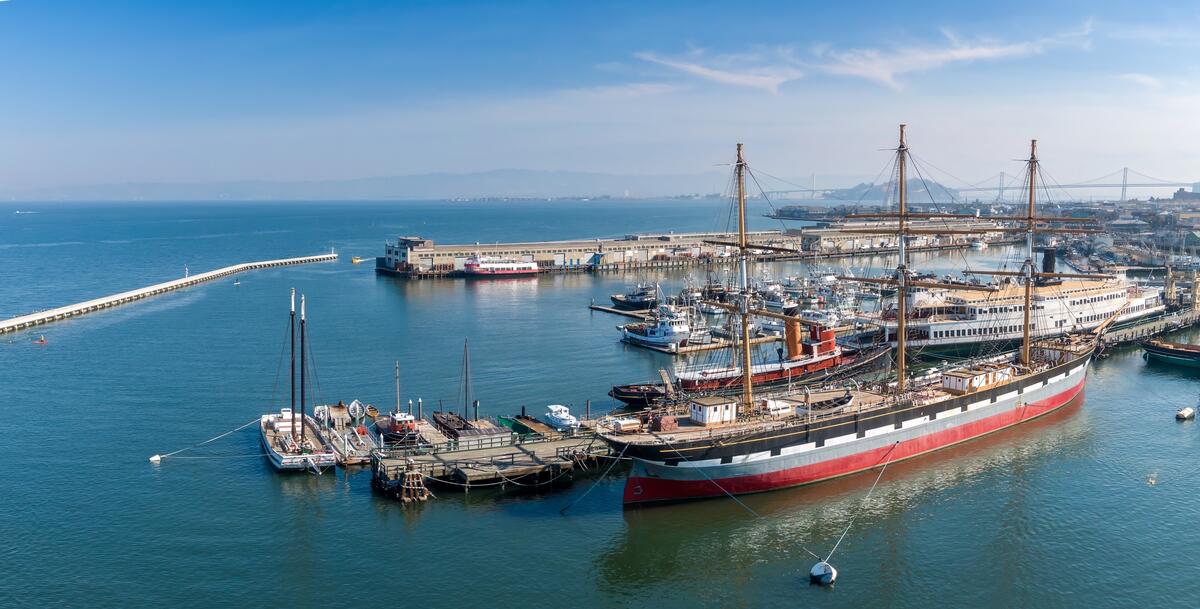 Die Luftansicht zeigt historische Schiffe mit hohen Masten und Takelage an ihrem früheren Liegeplatz am Hyde Street Pier.