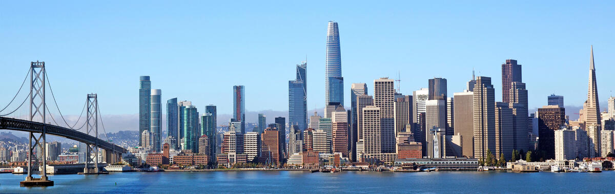 Blick vom Wasser auf die Hochhäuser von San Francisco, mit einem Teil der Bay Bridge am linken Bildrand.
